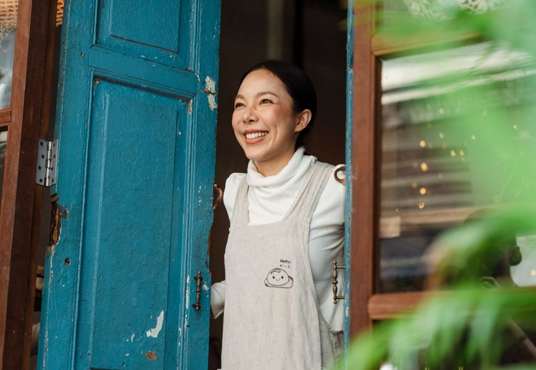 A cafe owner smiling in her doorway